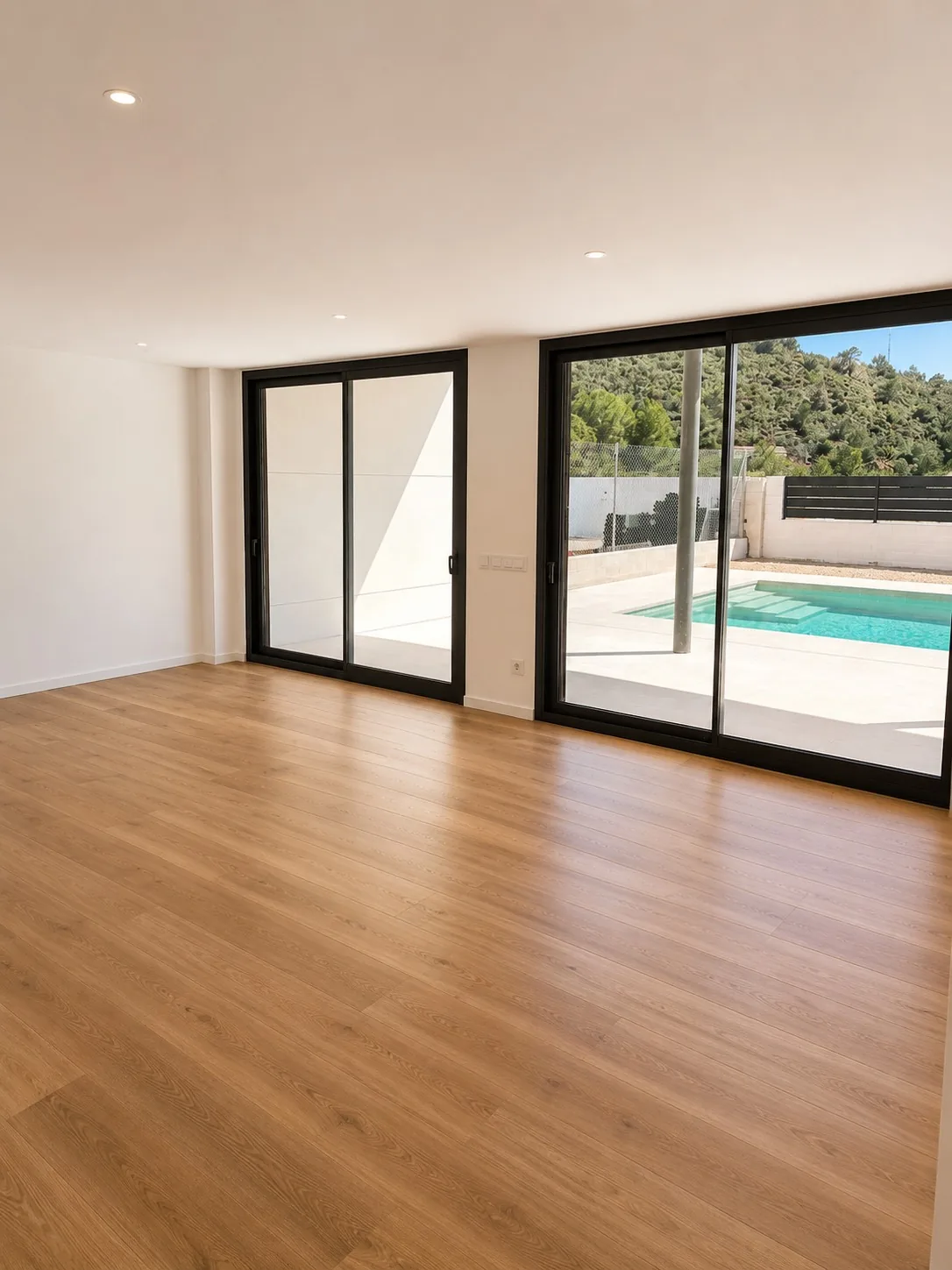 Estancia con suelo de madera abierta a la terraza y la piscina